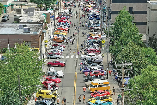 Classic cars line a busy stretch of road