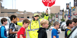 A crossing guard holds a stop sign while kids cross the street