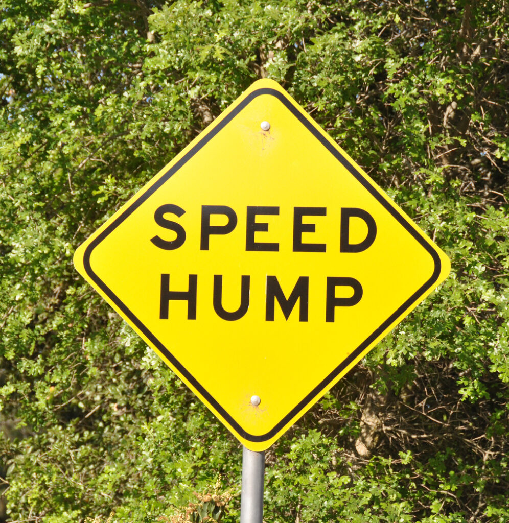 Yellow sign with words "Speed Hump"