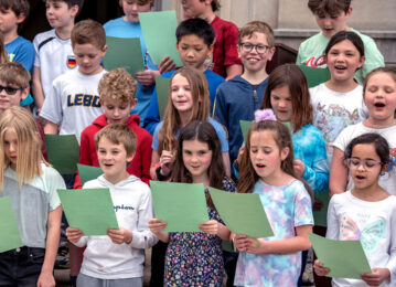 A group of children singing, while holding music sheets