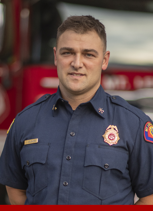 Deputy Chief of Community Outreach and Marketing Larry Celender standing in front of a fire engine