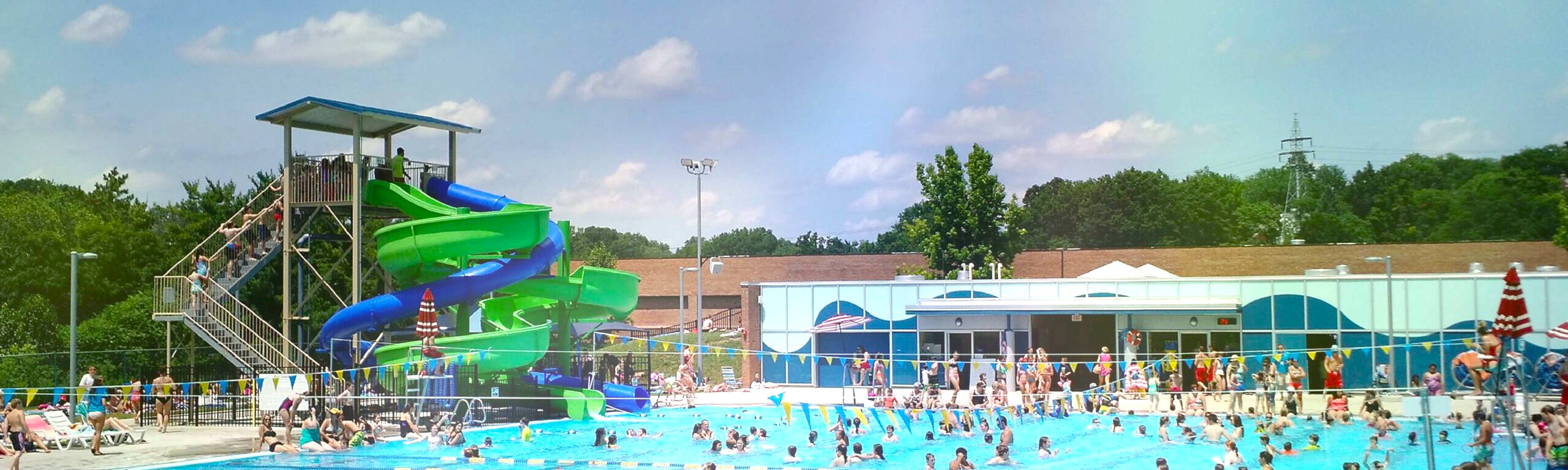 A filled swimming pool, with a large slide to the left